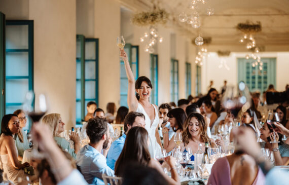 una sposa alza il bicchiere per brindare con gli invitati del suo matrimonio