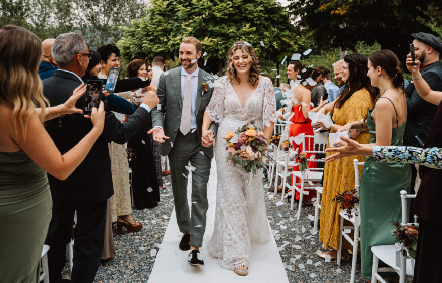 due sposi camminano mentre gli invitati lanciano loro petali