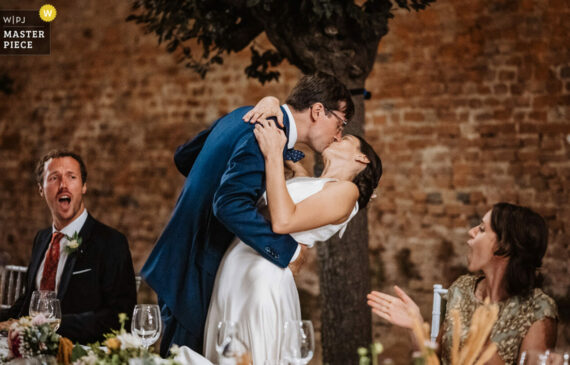 due sposi si baciano durante la cena del loro matrimonio