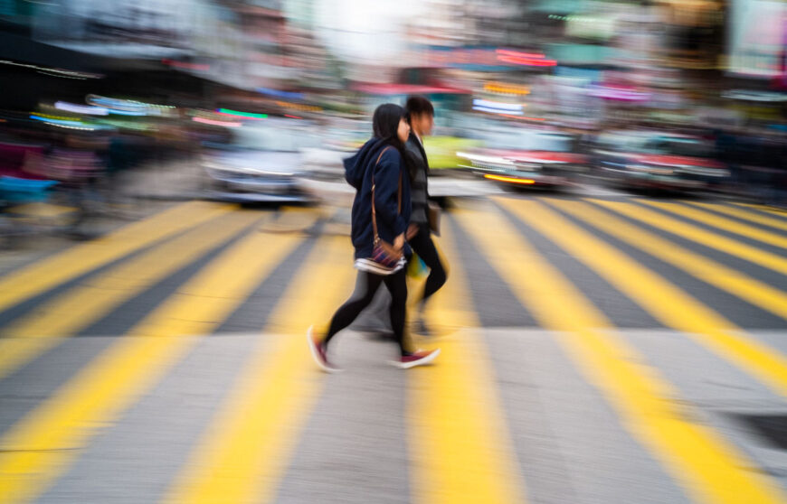 due ragazzi camminano su delle strisce pedonali gialle a Hong Kong