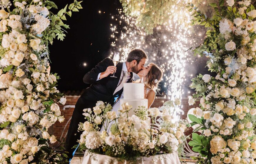 due sposi si baciano durante il taglio della torta del loro matrimonio presso i Giardini la Pergola di Alessandria